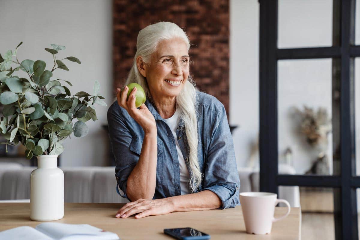 woman smiling holding apple.