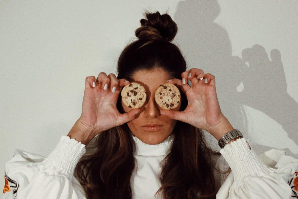 woman holding cookies over eyes.