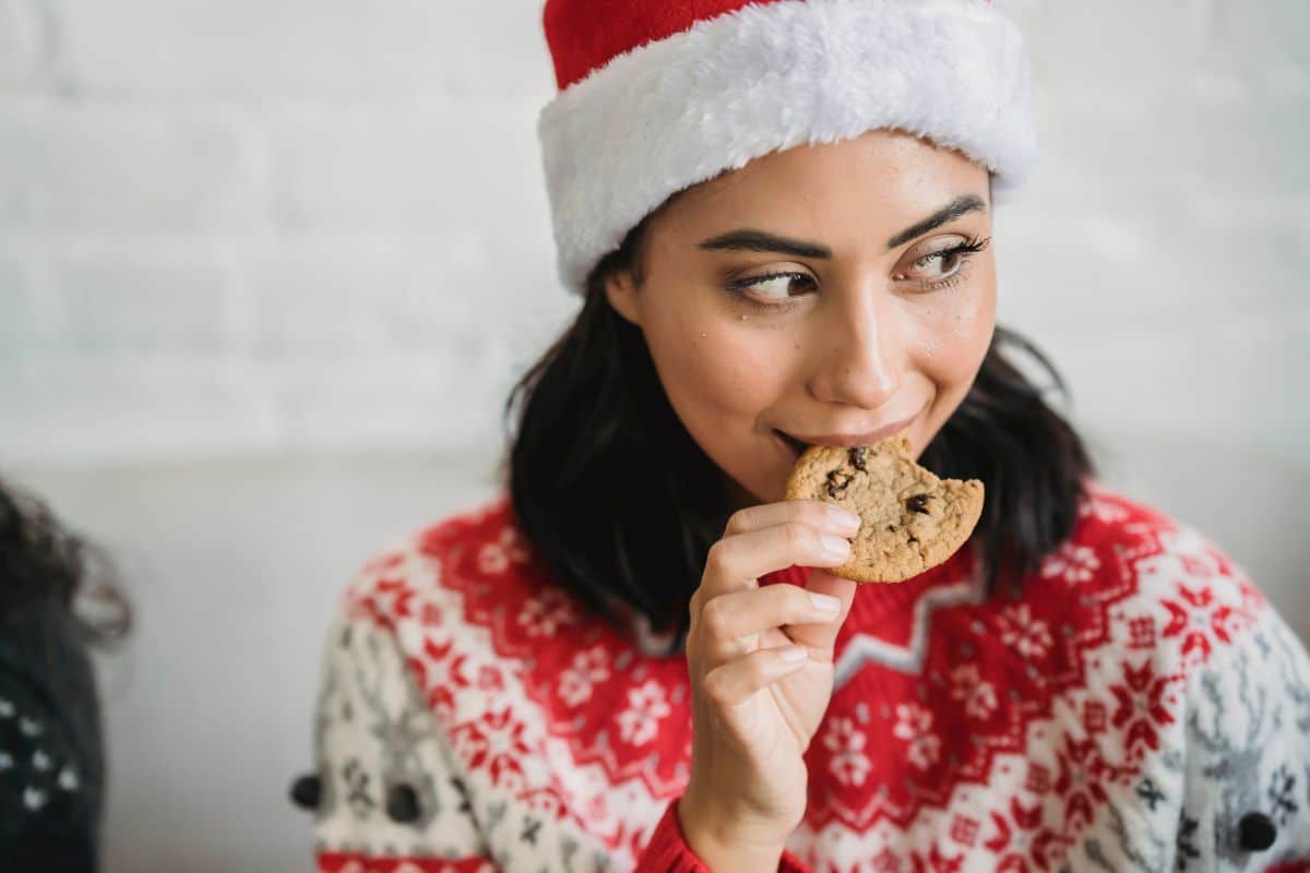 woman eating cookie wearing hat.