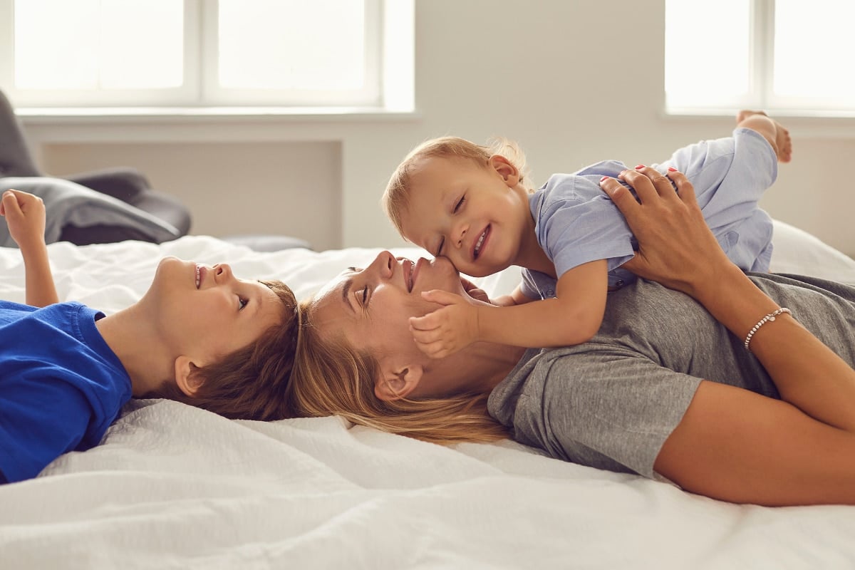 happy Mom on bed with kids.
