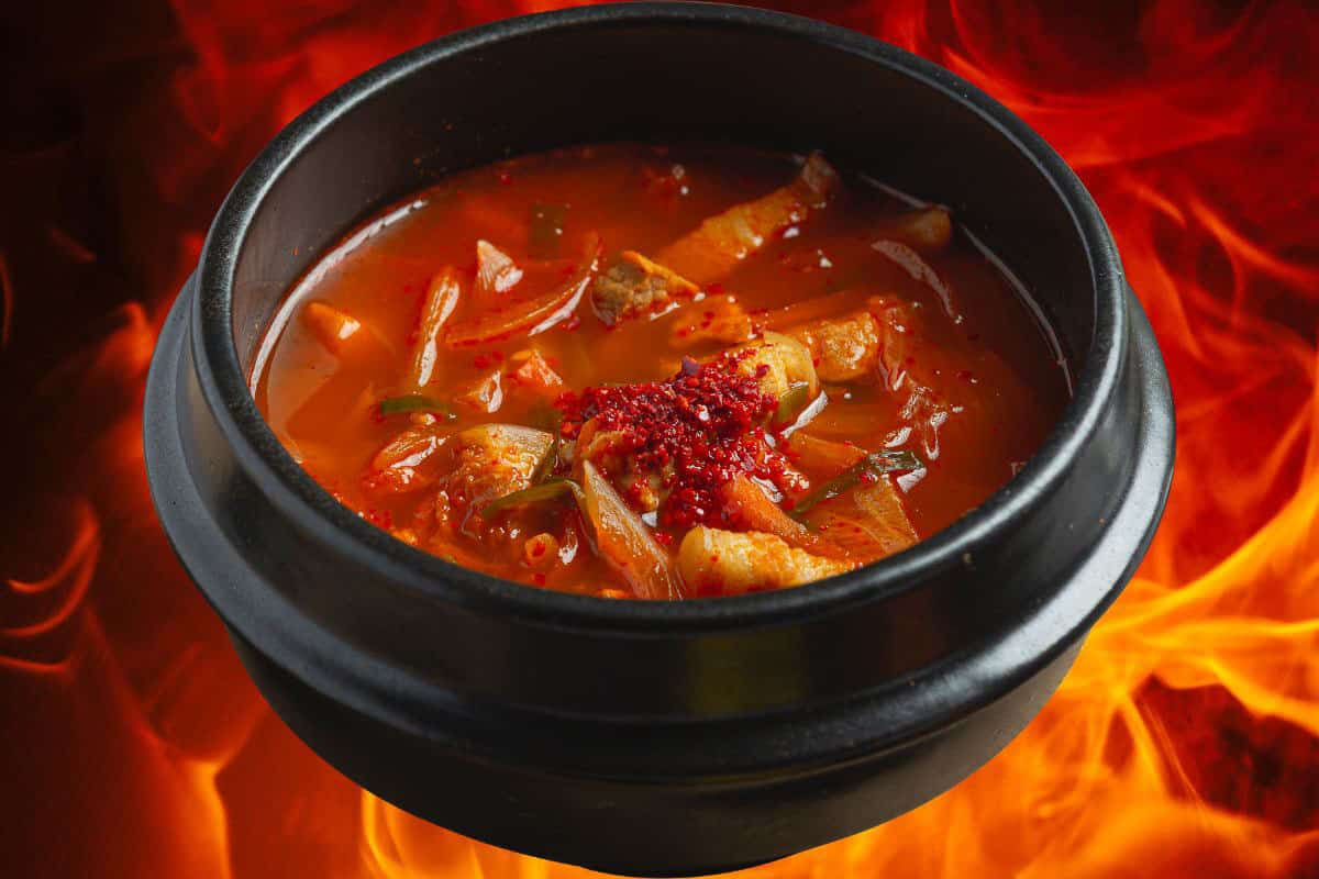 Hot food in pot against fiery background