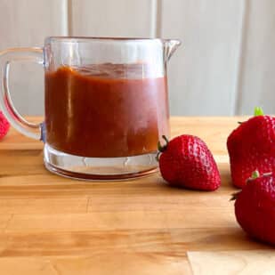 Low FODMAP Strawberry Chipotle BBQ Sauce in pitcher with berries alongside.
