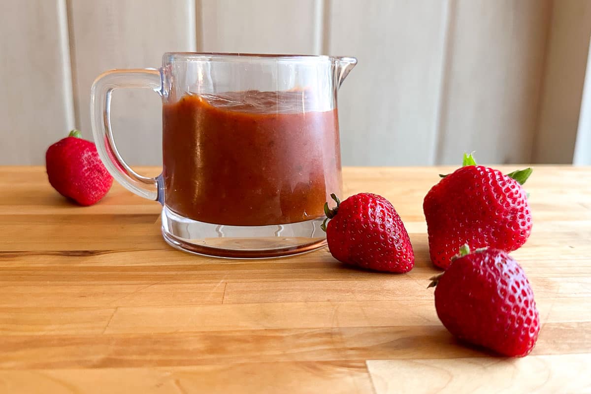 Low FODMAP Strawberry Chipotle BBQ Sauce in pitcher with berries alongside.