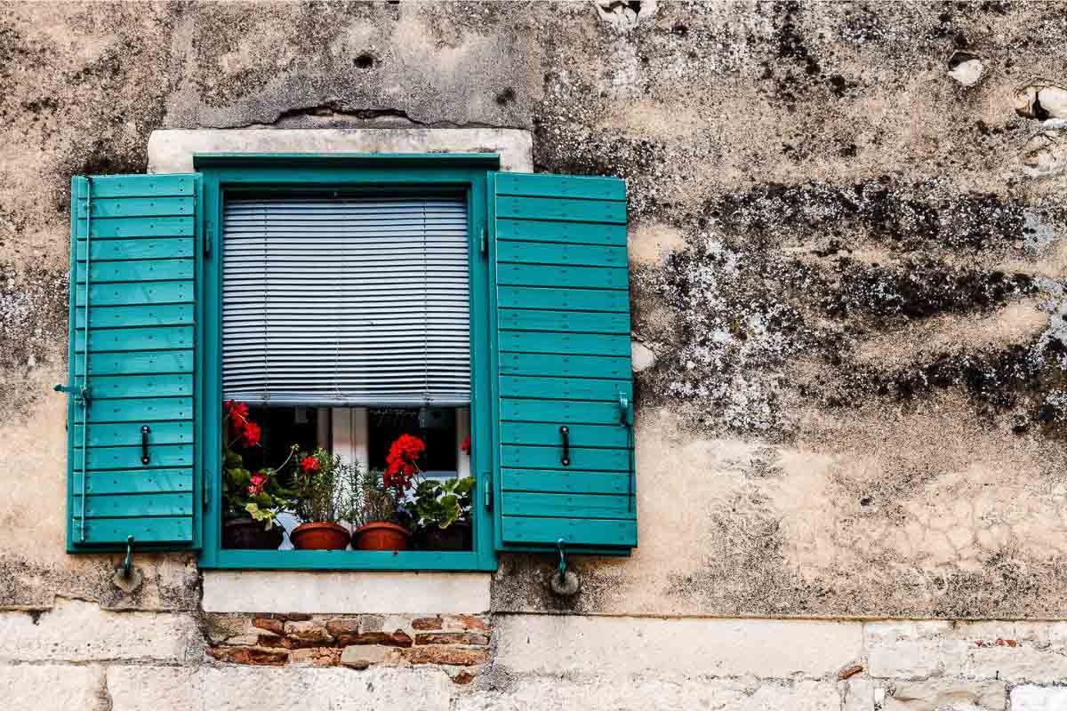 teal colored shutters on window.