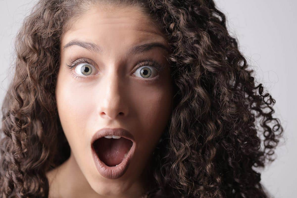 woman with curly hair looks shocked.