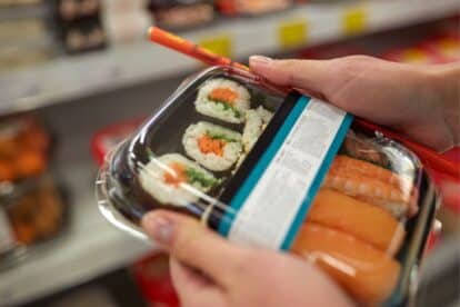 hand holding a package of supermarket sushi