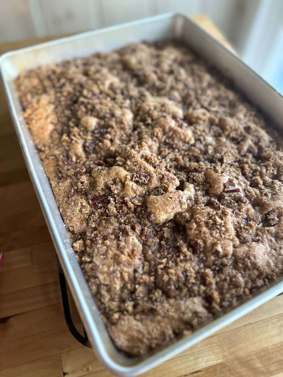 brown sugar pecan streusel topping over apple cake batter in pan before baking on rack.