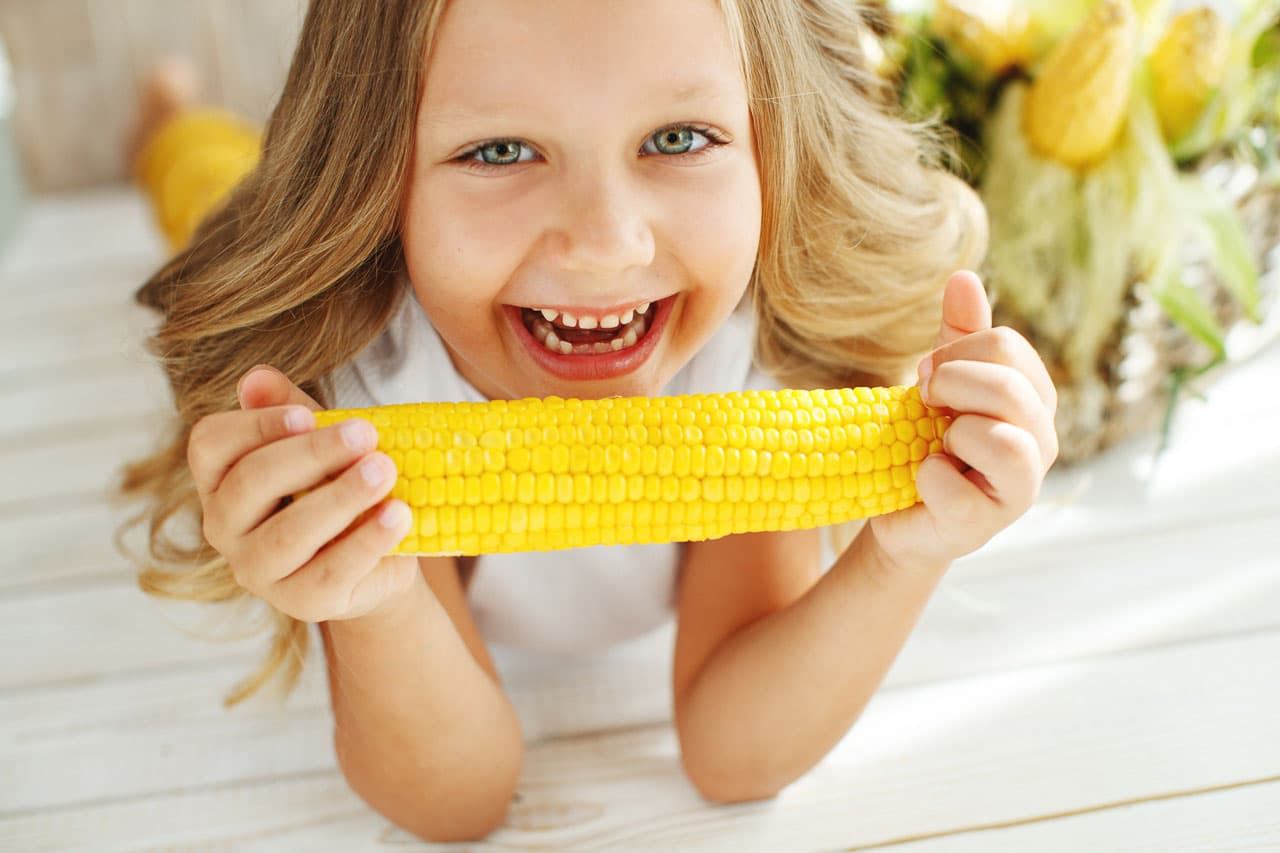 girl eating corn on cob.