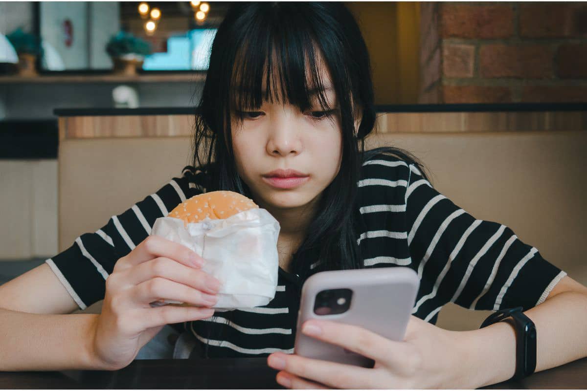 girl looking at phone while eating.
