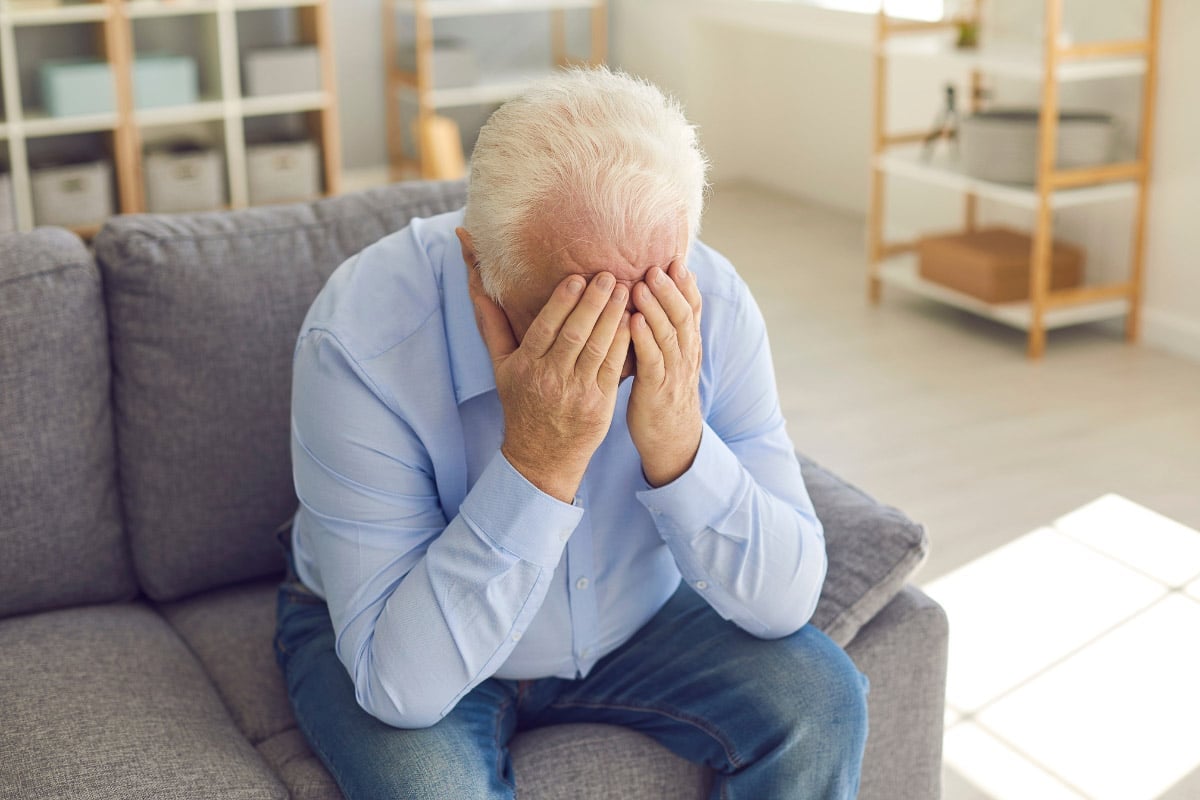 older man head in hands.