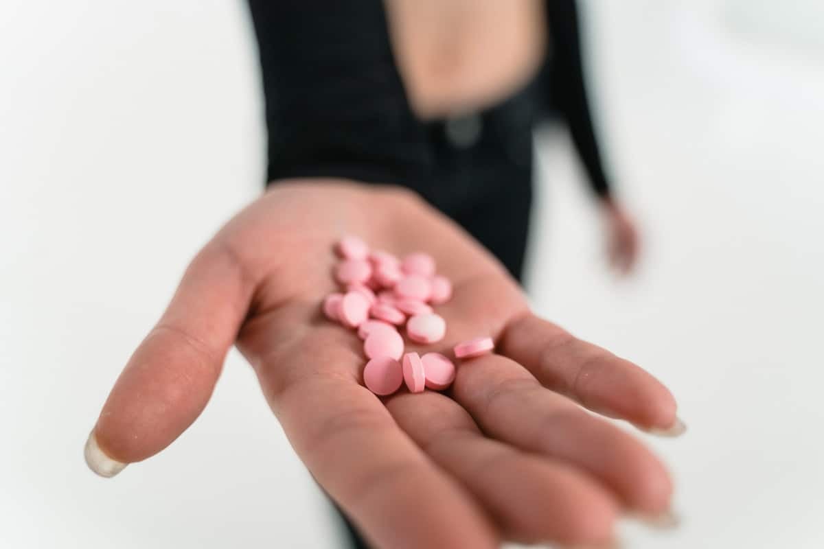 woman's hand with pink pills.