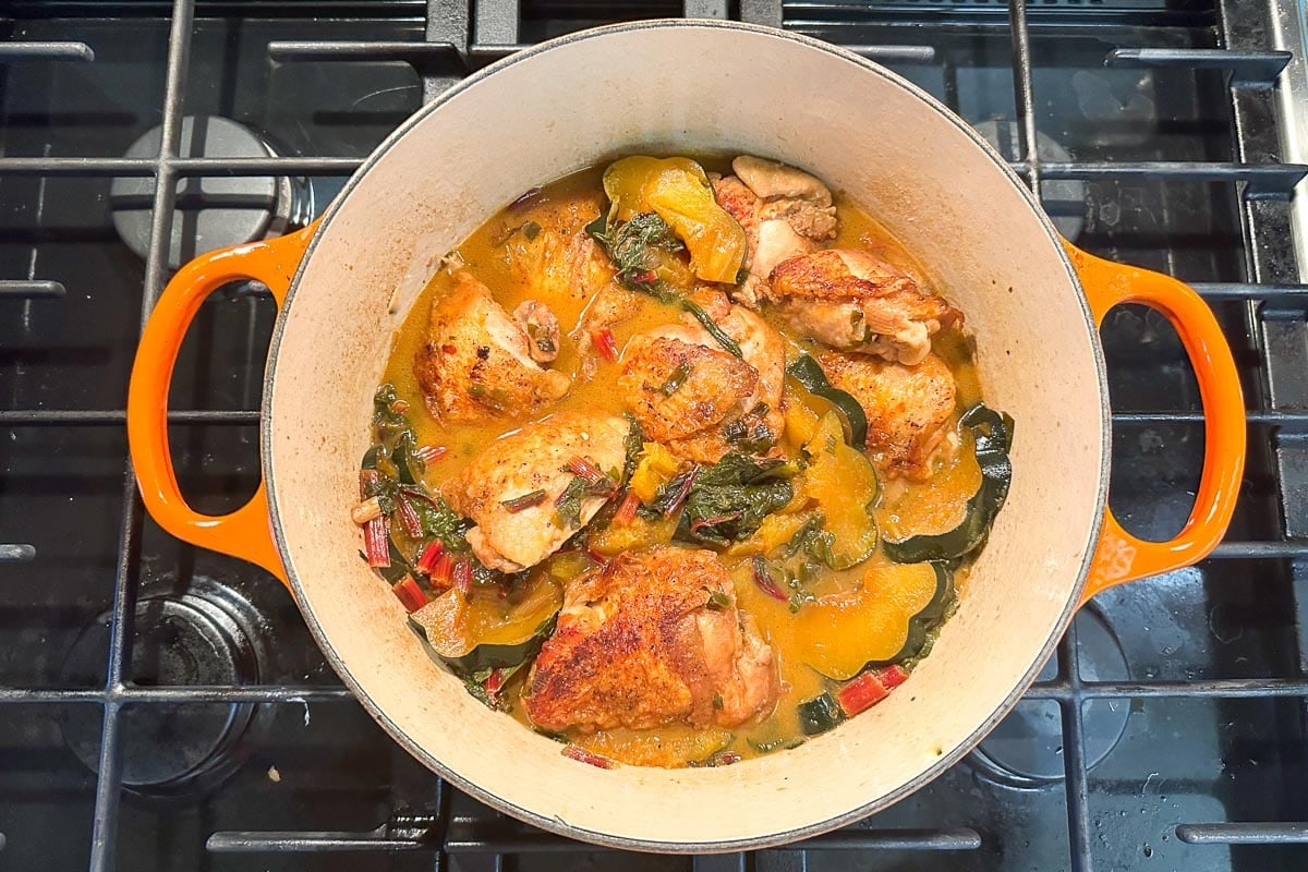 One-Pot Low FODMAP Braised Chicken with Swiss Chard and Acorn Squash in pot on stove.