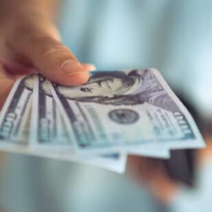 Female hands counting US Dollar bills or paying in cash .