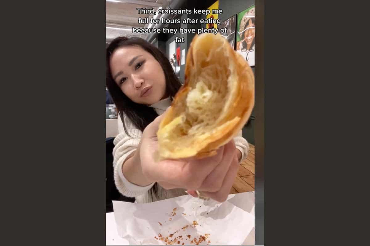 Woman eating croissant.