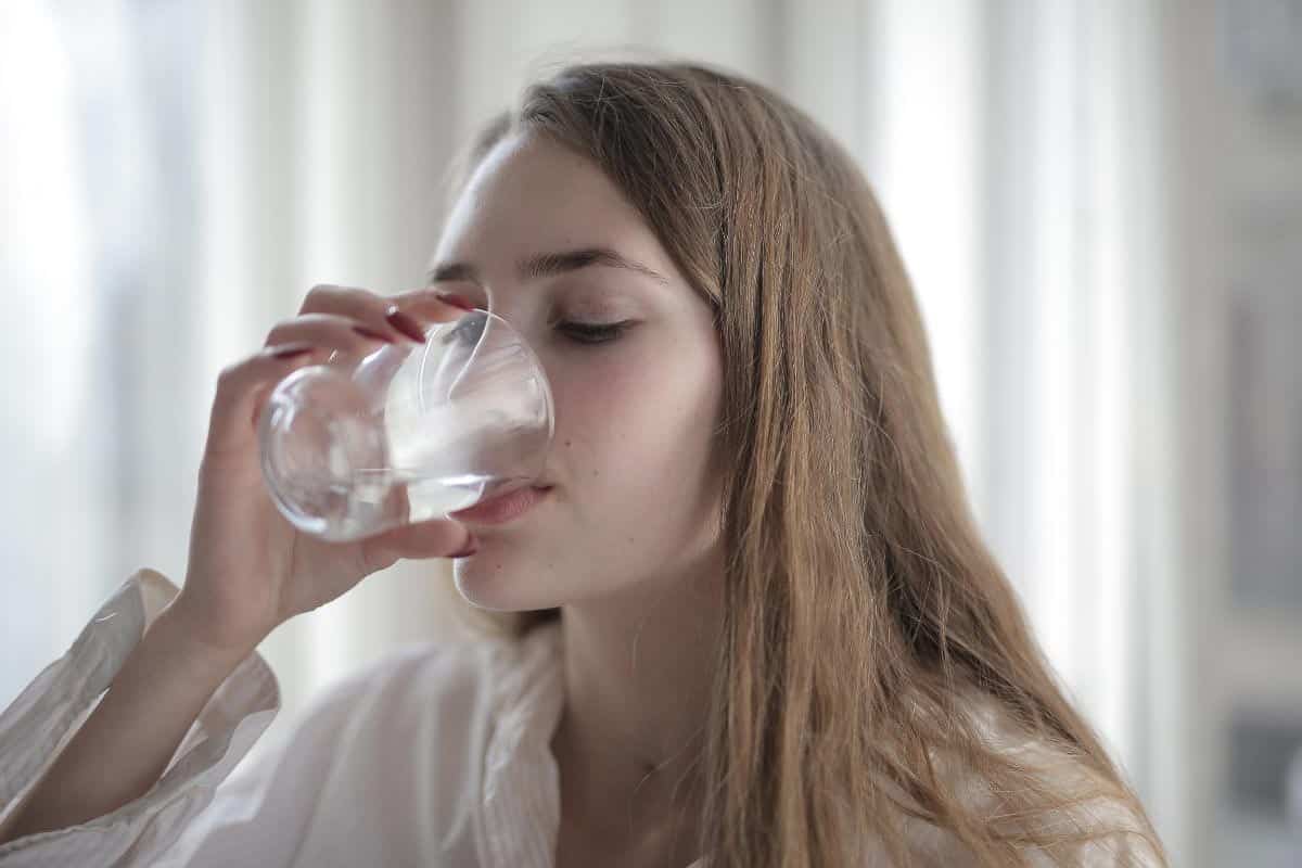 woman drinking water from clear glass.