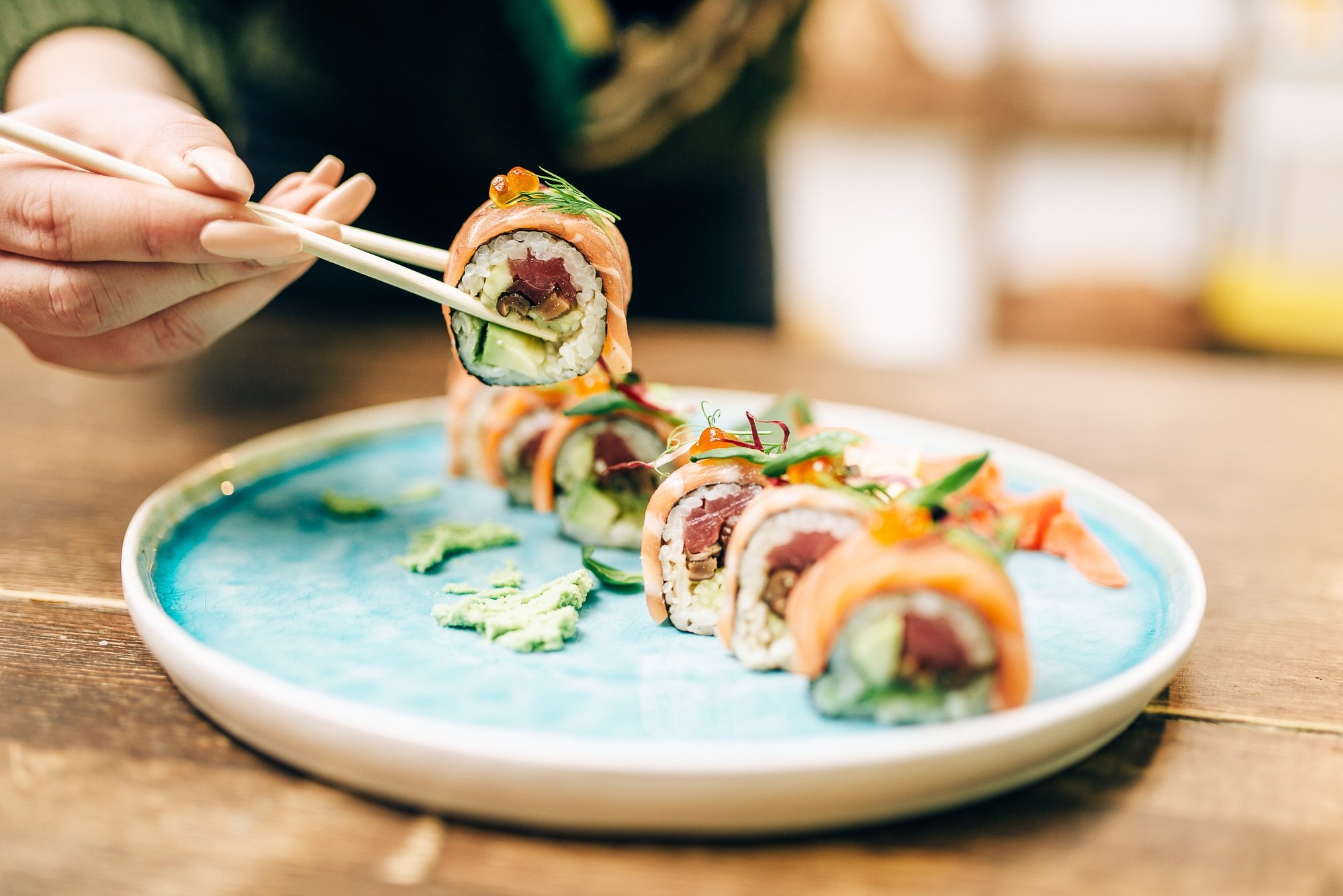 woman eating sushi with chopsticks.