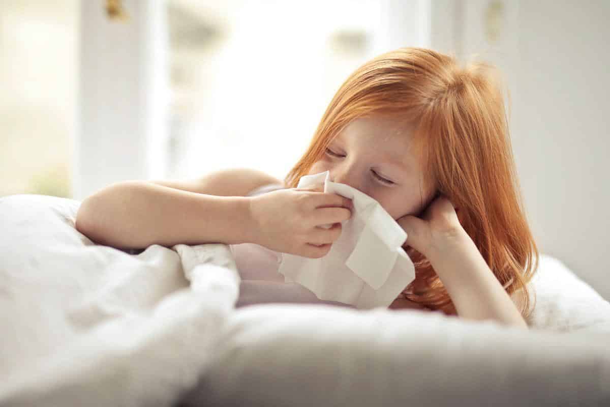 young redhead girl blowing nose.