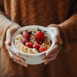 woman holding bowl of granola and fruit in her hands.
