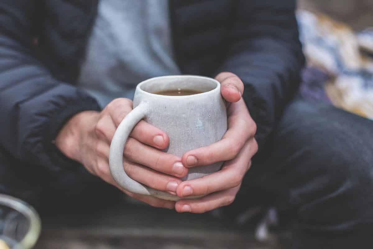 man holding mug of hot beverage.