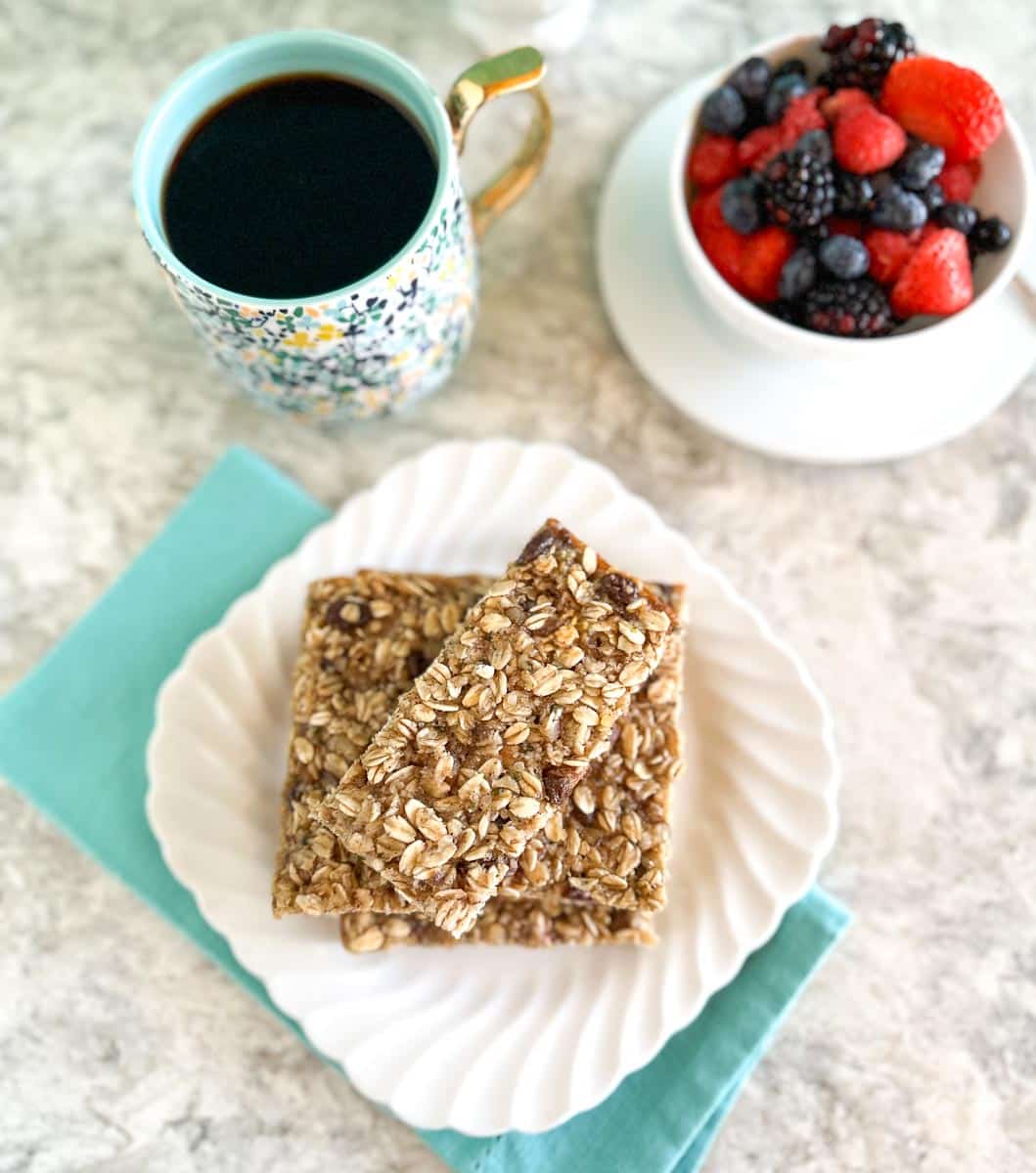 vertical Low FODMAP Breakfast Bars stacked on white plate, with aqua napkin.