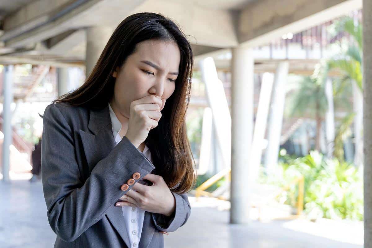 woman sneezing into hand.
