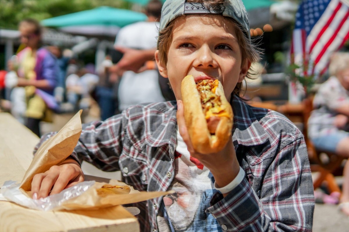 Boy eating a hot dog.