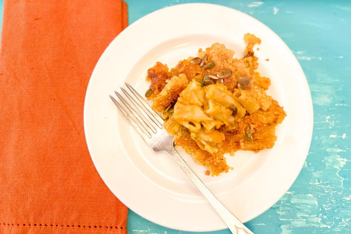 Low FODMAP Pumpkin Mac n Cheese on white plate with fork and napkin.