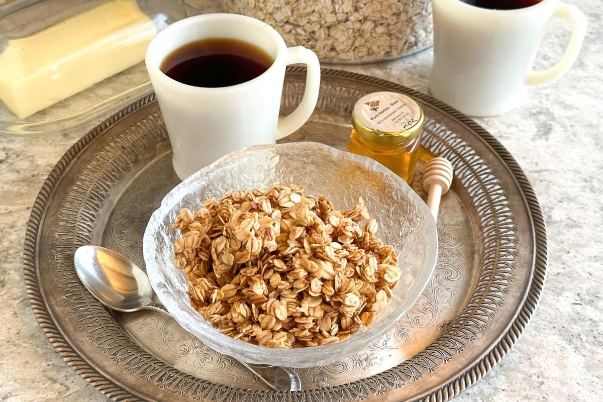 Low FODMAP 5-Minute Skillet Honey Butter Granola in glass bowl on silver platter.