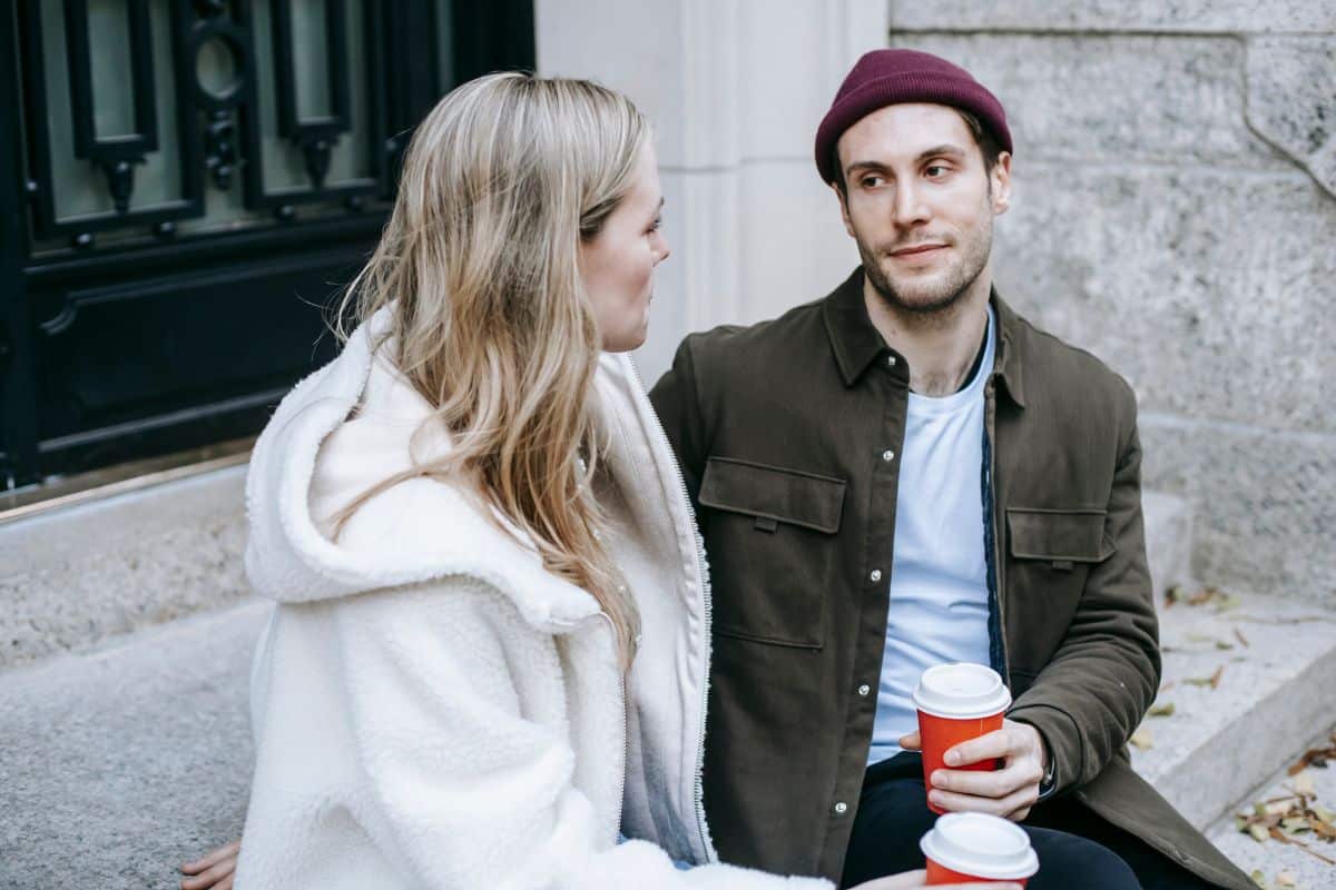 Man and woman sitting on steps outdoors. 