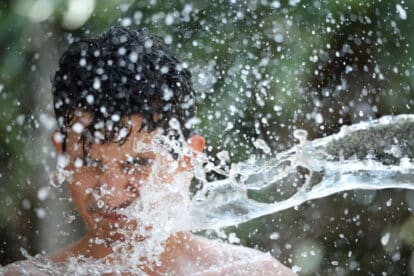 headshot of teen boy getting splashed of water.