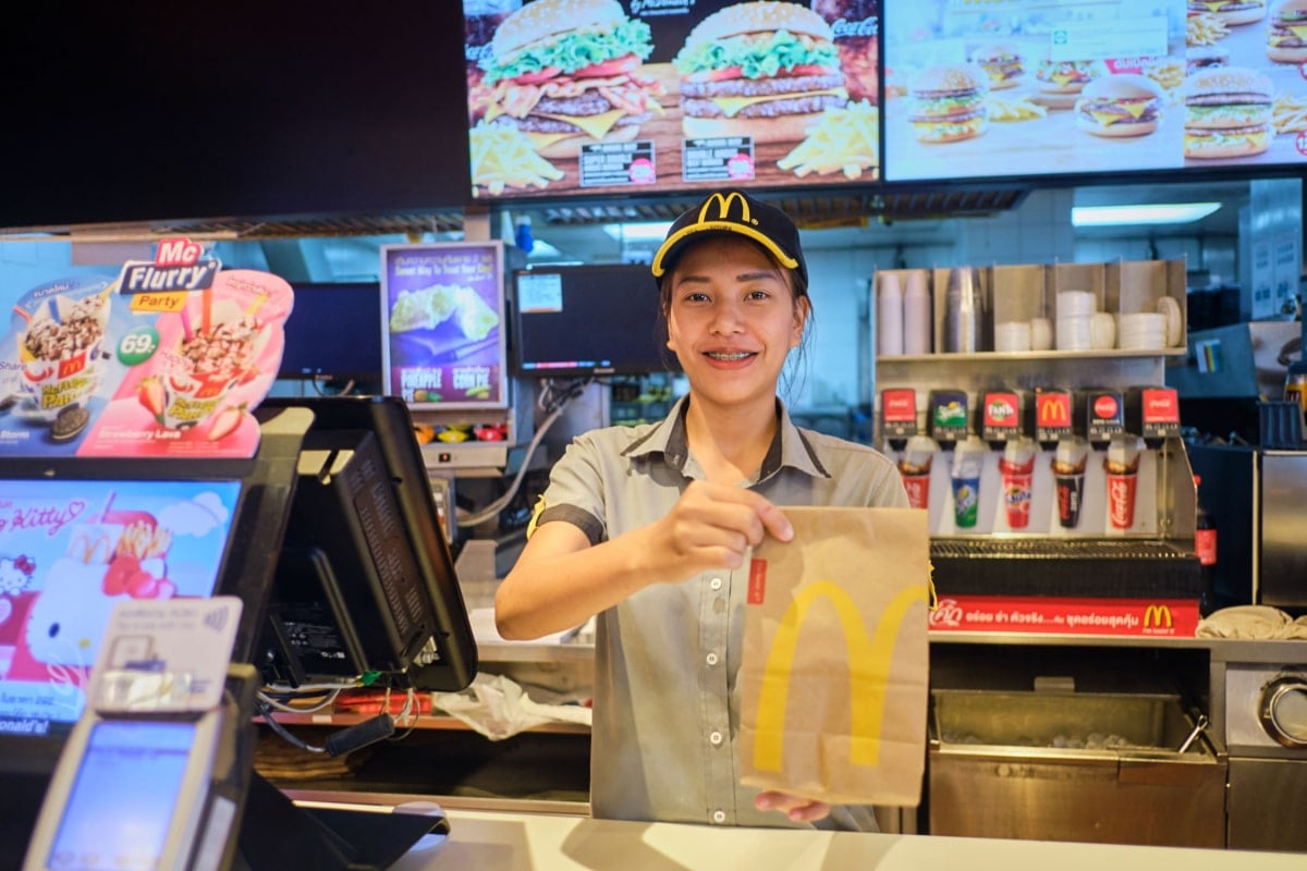Young part-time student workers smiling while handing McDonald's Brown Bag to customer at McDonald's restaurant, McDonald's is an American fast food restaurant.