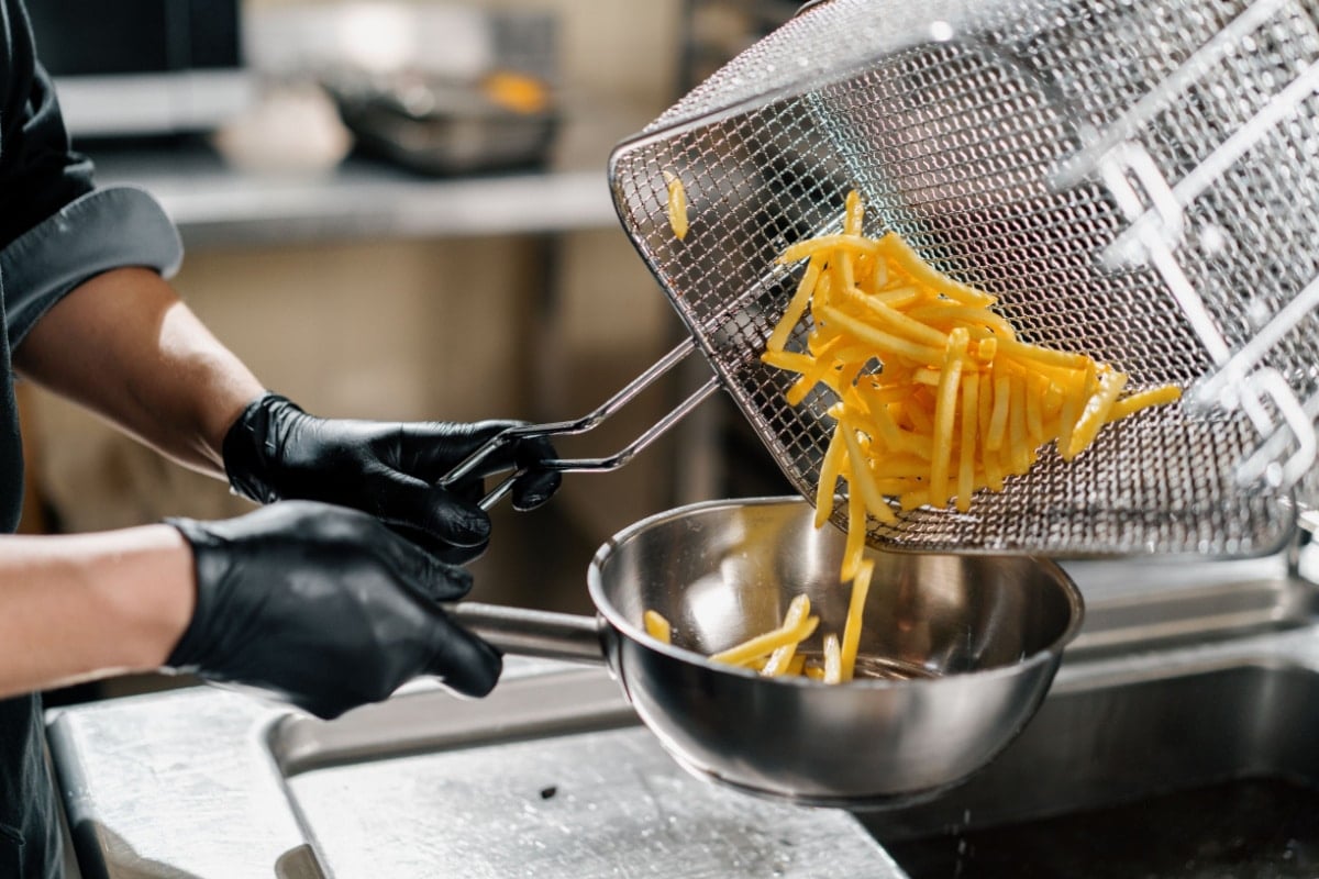 professional kitchen in restaurant of the hotel the chef takes out delicious french fries from the fryer.