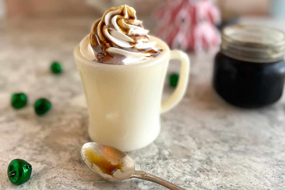 closeup, horizontal image of Low FODMAP Gingerbread Syrup drizzled on top of a latte with whipped cream.