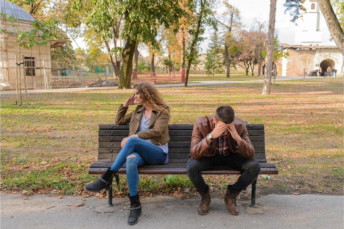 couple sitting on bench, upset.