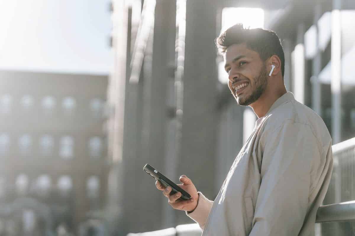 happy man using iPhone with earbuds. 