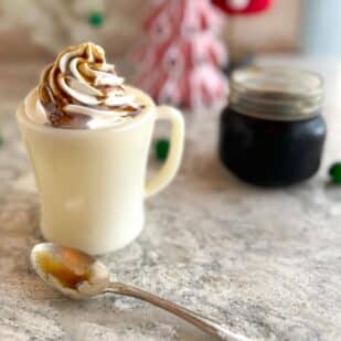 horizontal image of Low FODMAP Gingerbread Syrup drizzled on top of a latte with whipped cream.