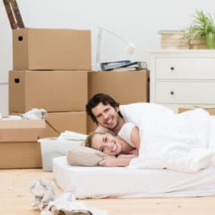 man and woman in bed on mattress on floor.