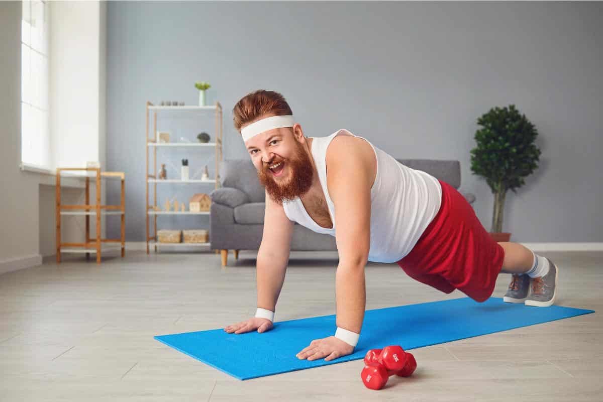 man in red shorts holding a plank.