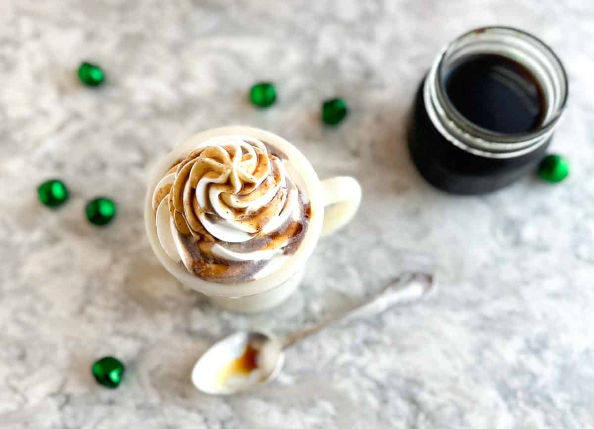 overhead image of Low FODMAP Gingerbread Syrup drizzled on top of a latte with whipped cream.