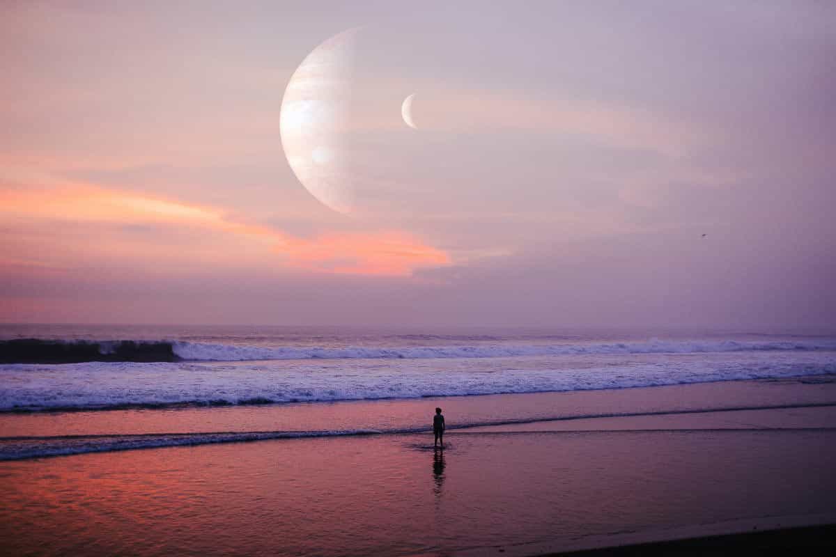 person on beach with sunset and planets in sky. 