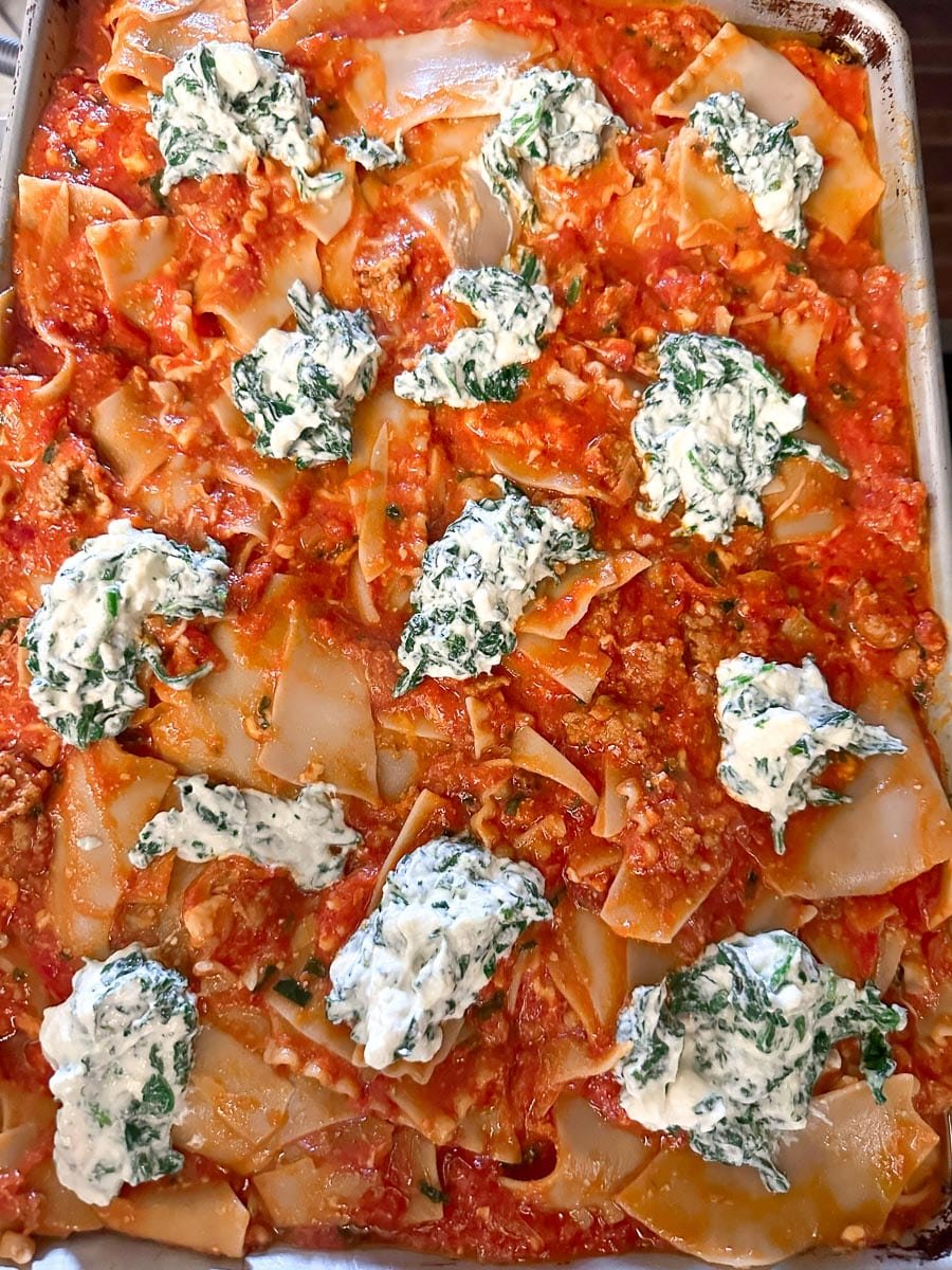 sheet pan lasagna on pan with dollops of ricotta.