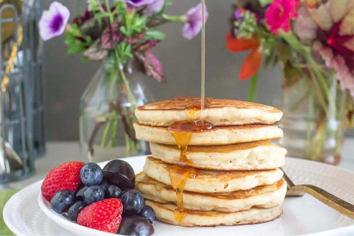 stack of Low FODMAP Fluffy Pancakes with syrup poured on top.
