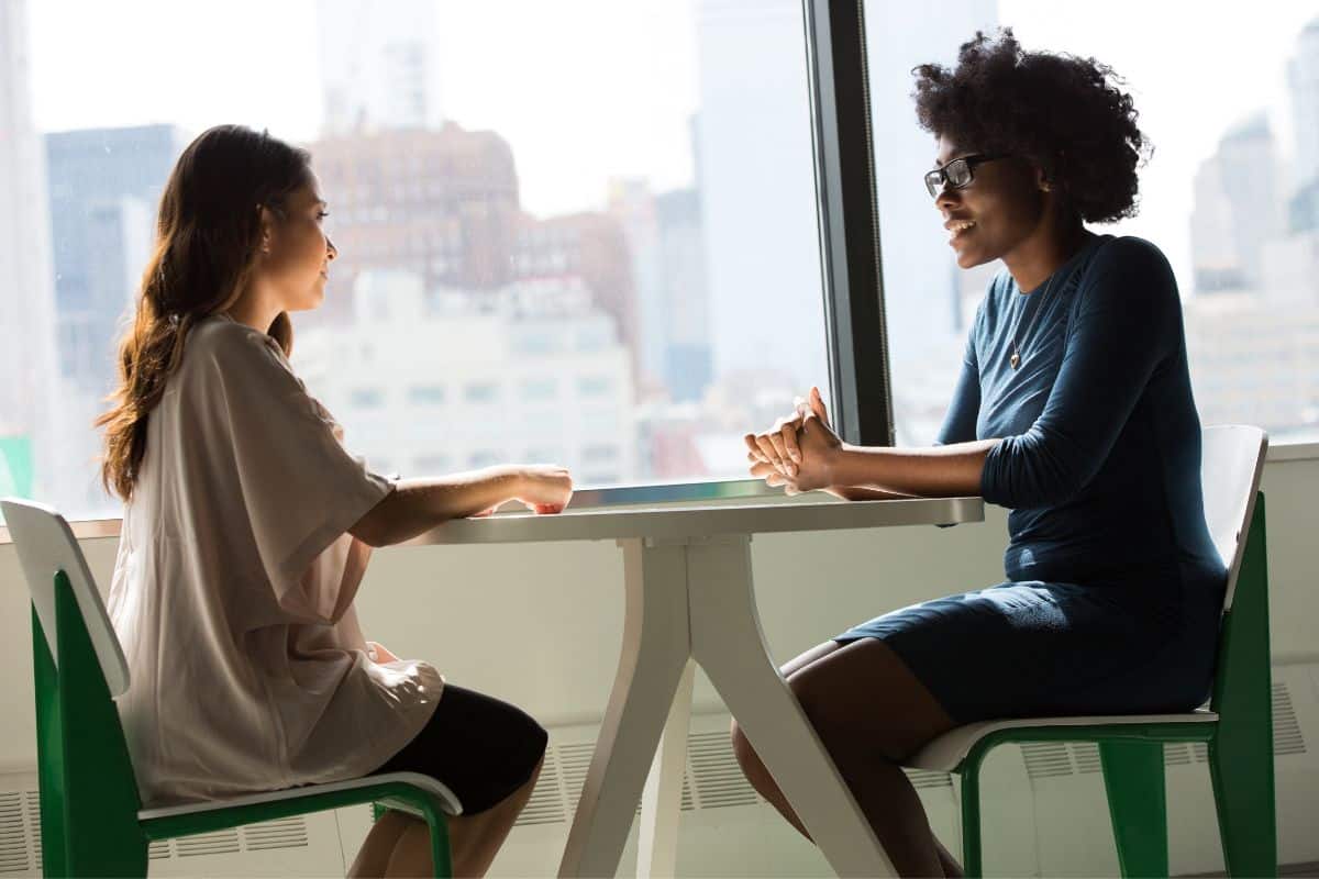 two women at table in front of window.
