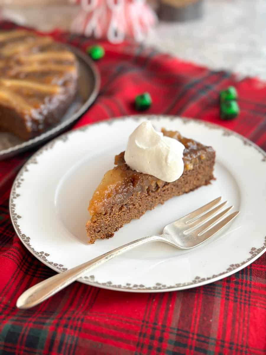 wedge of Lower FODMAP Gingerbread Pear Upside Down cake on plate, with whipped cream.
