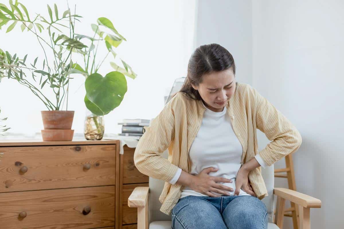 woman sitting in chair clutching stomach. 