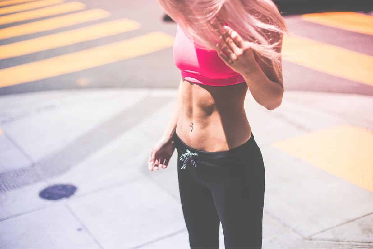 woman with belly ring wearing pink crop top. 