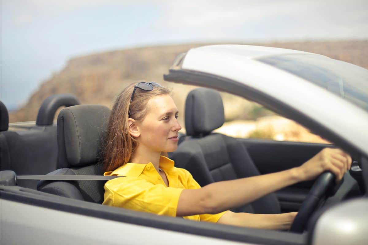 young woman in yellow shirt driving a car.