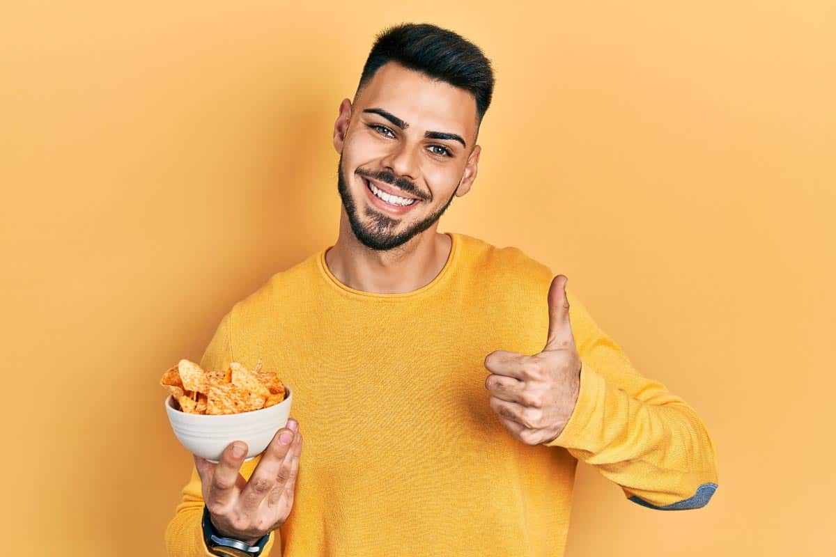 Man with bowl of chips. Shutterstock_2019226421.