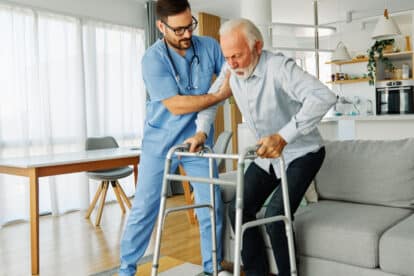 Doctor or nurse caregiver with senior man using walker assistanece at home or nursing home