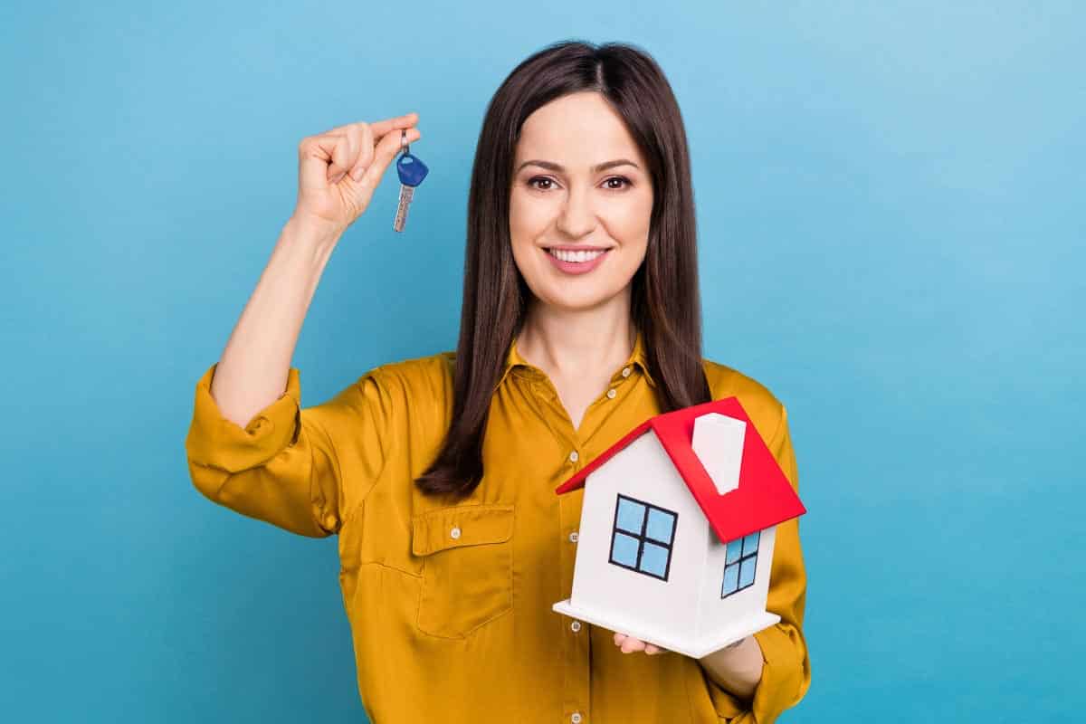 woman holding model house. Shutterstock_2273090743.